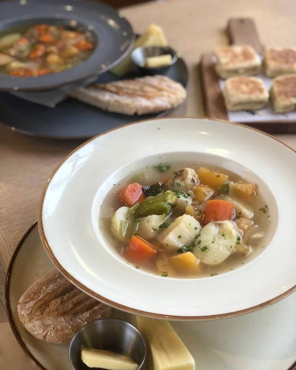 A bowl of vegetable cawl with bread and Welsh cakes at MamGu's Kitchen